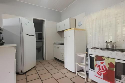 a kitchen with a white refrigerator and a stove at Chalé frente mar na Ilha do Mel - Encantadas. in Ilha do Mel