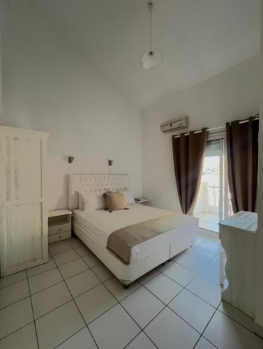 a white bedroom with a bed and a window at Villa Apostolidis in Skala Potamias