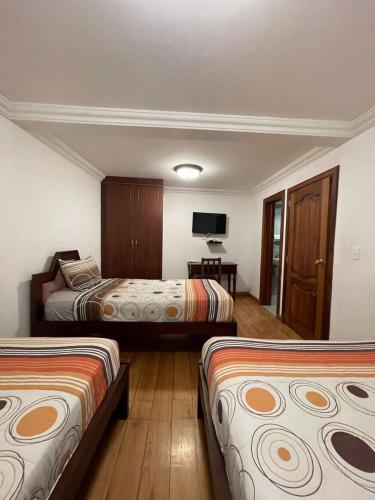 a hotel room with two beds and a television at Riberas del Valle in Cuenca