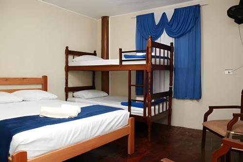 two bunk beds in a room with blue curtains at Casa da Ale e do Thi - Ilha do Mel in Ilha do Mel