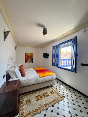 a bedroom with a bed and a window and a rug at Riad Zawia in Essaouira