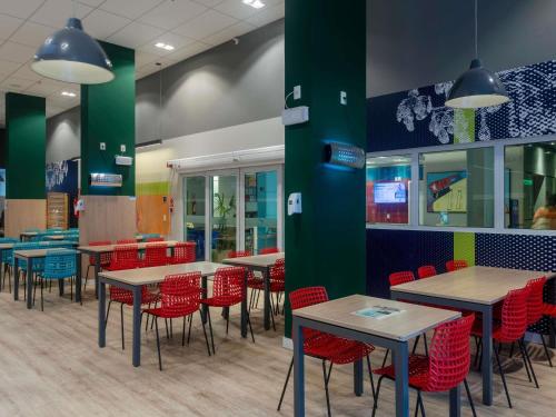 a dining room with tables and red chairs at ibis budget Maceió Pajuçara in Maceió