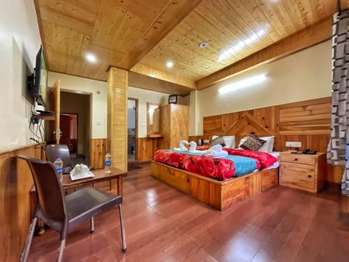 a bedroom with a bed and a desk and a chair at Katha Inn in Manāli