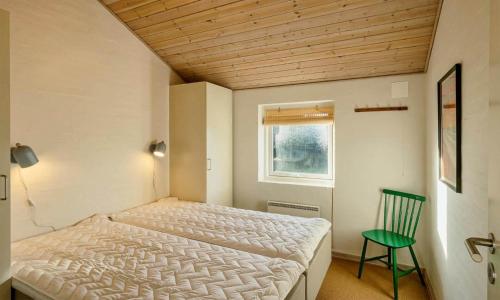 a bedroom with a bed and a green chair at VE087-Vejers-Strand-Jafdalvej-41 in Vejers Strand