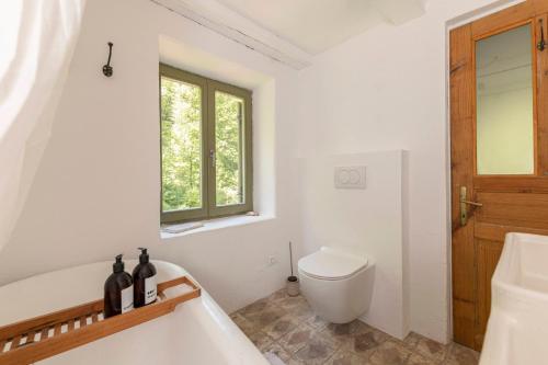 a bathroom with a tub and a toilet and a window at Klavze 28 in Most na Soči