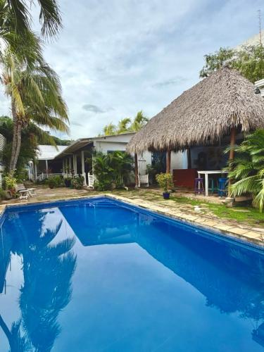 a resort with a blue swimming pool with a thatch roof at La Posada Azul Boutique Hotel Coco SA in San Juan del Sur