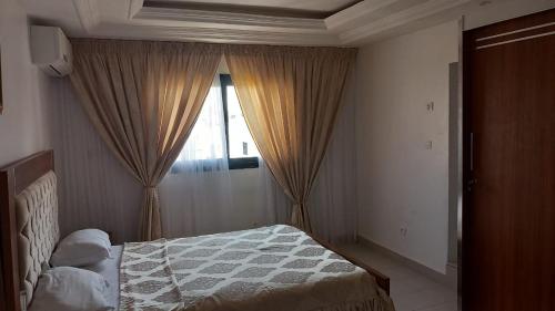 a bedroom with a bed and a window with curtains at Elite appart in Dakar