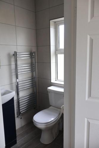 a bathroom with a white toilet and a window at Beach view Bungalow in Spanish Point