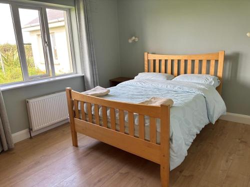 a wooden bed in a bedroom with a window at Beach view Bungalow in Spanish Point