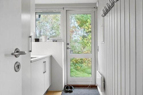 a white kitchen with two windows and a sink at 1077-Thisted-Johns-Vej-33 in Klitmøller