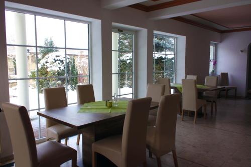 ein Esszimmer mit einem Tisch, Stühlen und Fenstern in der Unterkunft Pension Finkenschenke in Gröditz