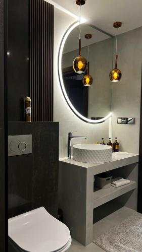 a bathroom with a sink and a mirror and a toilet at Sadowa Ostoja z prywatnymi jacuzzi in Pierwoszyno