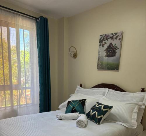 a bedroom with a bed with white sheets and a window at Savana Abode-Nakuru CBD in Nakuru