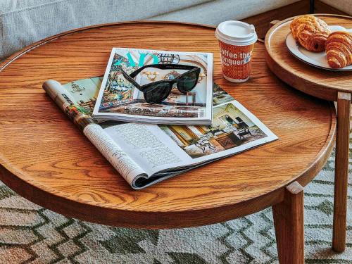 a table with a book and a magazine and a cup of coffee at 25hours Hotel Dubai One Central in Dubai