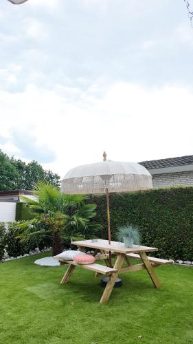 a picnic table with an umbrella on the grass at ViVe in Putten