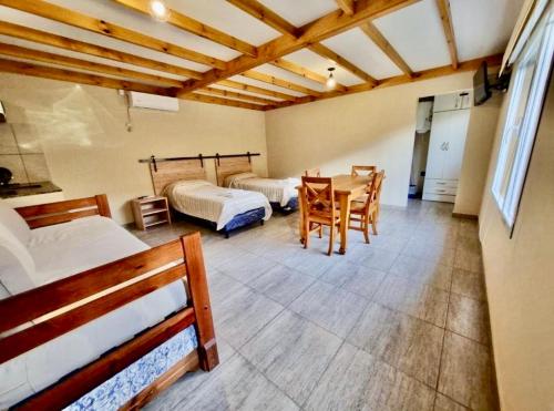 a room with two beds and a table and chairs at Las lupinas pleno centro in Coronel Suárez