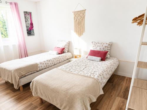 two beds in a room with white walls and wood floors at Le petit paradis in Abbeville