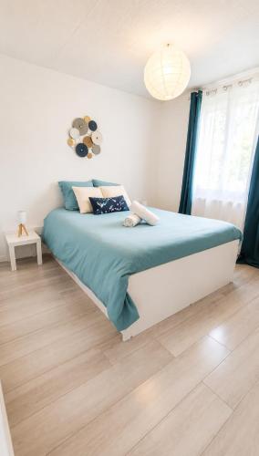 a bedroom with a bed with a blue comforter at Le petit paradis in Abbeville