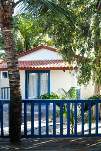 a blue fence in front of a house with a palm tree at Pousada Vila Pequi in Barreirinhas