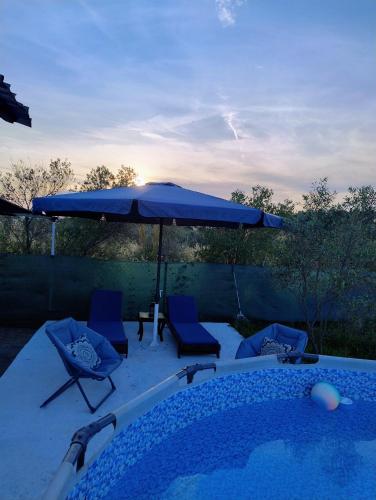 a swimming pool with a blue umbrella and chairs at Tiny Loft House in Halkidiki in Nea Potidaea