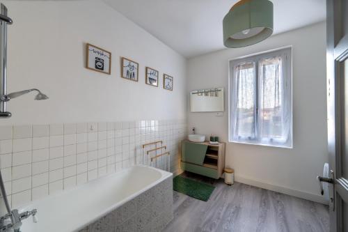 a white bathroom with a tub and a window at La lande appart in Tranzault