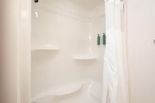 a bathroom with a shower with a white shower curtain at Tugboat Inn in Boothbay Harbor