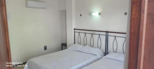 two beds in a small room with white walls at Hotel San Carlos in Tizimín