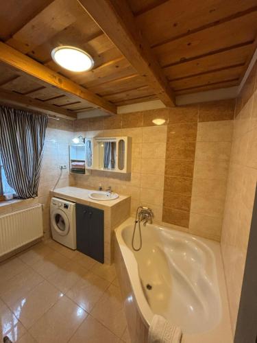 a bathroom with a tub and a sink and a washing machine at Kinga House in Keszthely