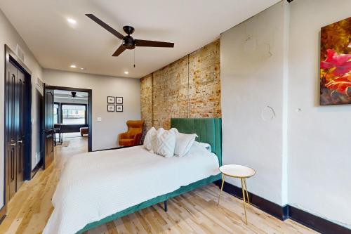 a bedroom with a white bed and a brick wall at Steps to Dtwn & Rock River! Couples Retreat in Janesville