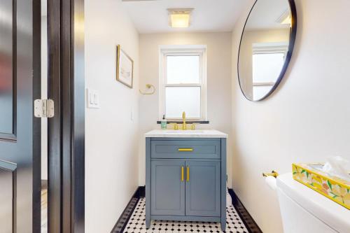a bathroom with a blue cabinet and a mirror at Steps to Dtwn & Rock River! Couples Retreat in Janesville