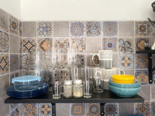 a shelf with plates and glasses on a tile wall at Estudio #2 a 5 min del malecon in La Paz