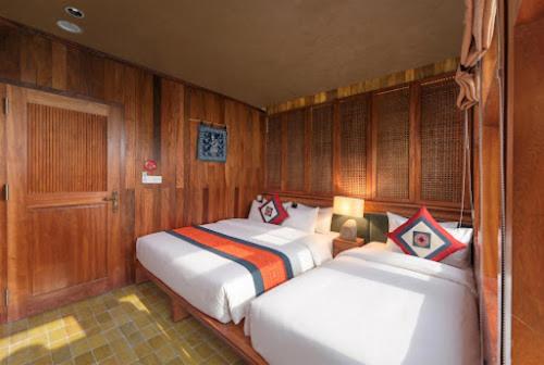 two beds in a room with wooden walls at Petit Prince Cruise in Cat Ba