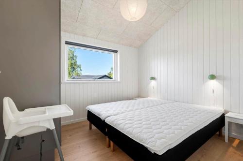 a bedroom with a white bed and a white chair at OH591-Storvorde-Pilekrogen-15 in Skelby