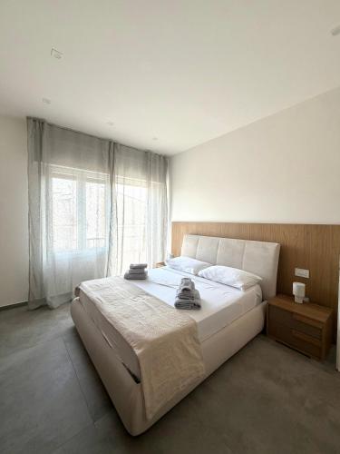 a bedroom with a large white bed and a window at Velù Apartment in Porto Viro