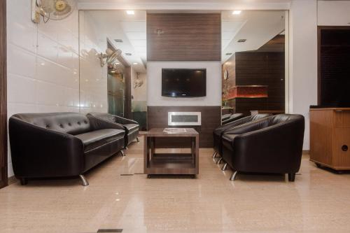 a living room with two leather couches and a tv at Super Hotel O Solitaire in Turambhe