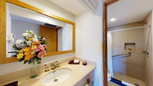 a bathroom with a sink and a mirror and flowers at Park Royal Beach Huatulco in Tangolunda