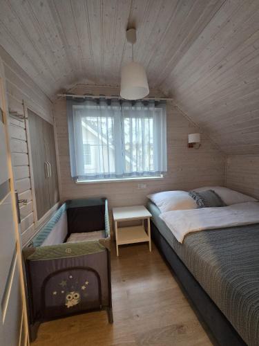 a small bedroom with a bed and a window at KANALOA in Pobierowo