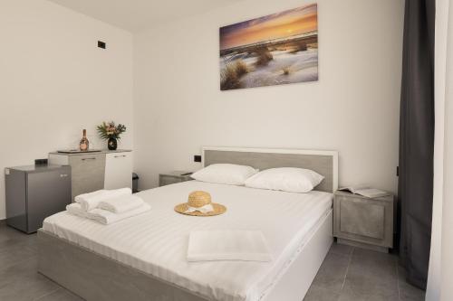 a white bedroom with a bed with a hat on it at Flamingo Corbu Resort in Corbu