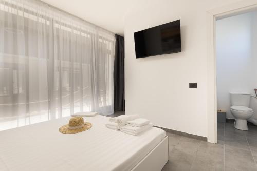 a white bedroom with a bed with a hat on it at Flamingo Corbu Resort in Corbu
