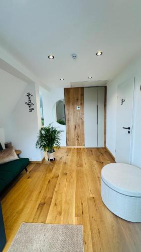 a living room with a couch and a wooden floor at Klimatisierte Komfort-Eifel-Ferienwohnung Mechernich, Obergartzem, Satzvey - nahe Krewelshof, Burg Satzvey & Phantasialand in Mechernich