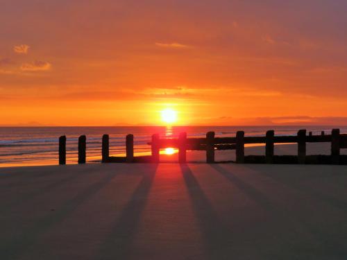 a person standing on the beach at sunset at Leamington House in Barmouth