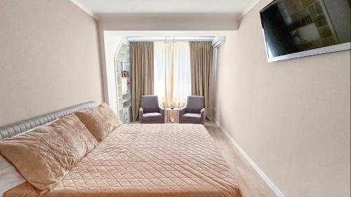 a hotel room with a bed and two chairs at Central cozy apartments- one and two bedrooms option in Chişinău