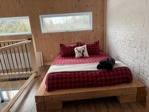 ein Bett mit einer karierten Decke und Kissen in einem Zimmer in der Unterkunft Oasis thermal Mauricie Chalet NE Chic Shack in Saint Mathieu Du Parc