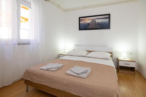 a bedroom with a bed with two towels on it at Apartments Baretić in Crikvenica