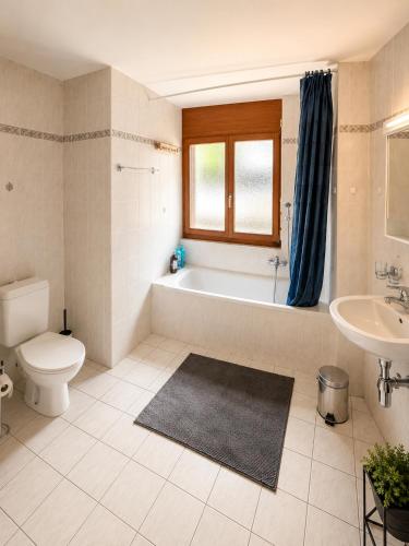 a bathroom with a tub and a toilet and a sink at Le Cormier - Appartement 6 personnes in Ovronnaz