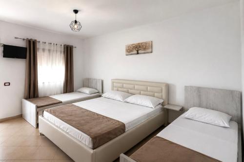 two beds in a bedroom with white walls at Hotel Aleksi Velipojë in Velipojë
