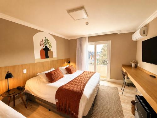 a hotel room with a bed and a television at Pousada Telhado de Ouro in Campos do Jordão