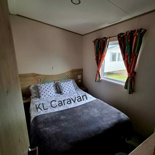 a bedroom with a large bed in a room with a window at KL Caravan in Prestatyn