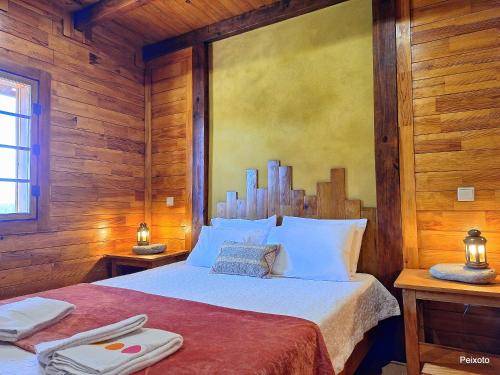 a bedroom with a large bed with wooden walls at Casa das Devesas in Caldelas
