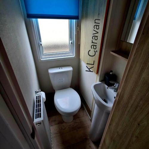 a small bathroom with a toilet and a sink at KL Caravan in Prestatyn